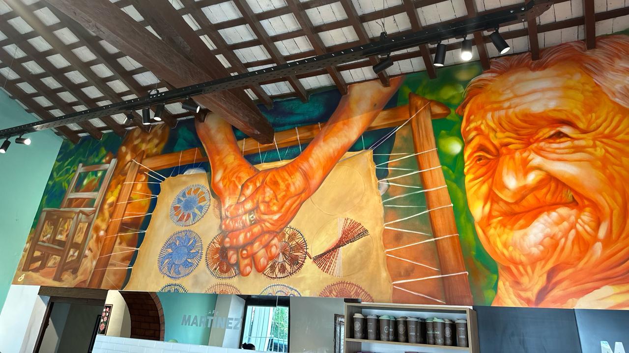Sobre una de las paredes de la sucursal de Café Martínez en Itauguá, el artista Oz Montania pintó un mural en honor a las tejedoras de ñandutí 